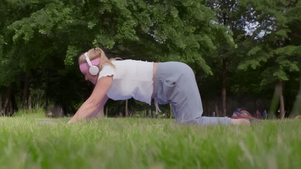 Side View of Fit Aged Woman Stretching on Fitness Mat in Park