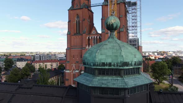 Gustavianum dome and Uppsala Cathedral with cityscape in background, Sweden. Aerial drone ascending