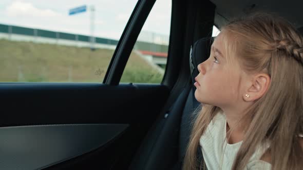 Caucasian girl of 8 years looking out of the car window while car trip.  Shot with RED helium camera