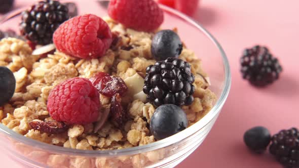 Granola and Berries in Bowl on Pink Background