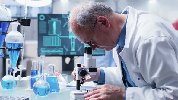 Close Up Dolly Shot of Mature Chemist Researching Using a Microscope