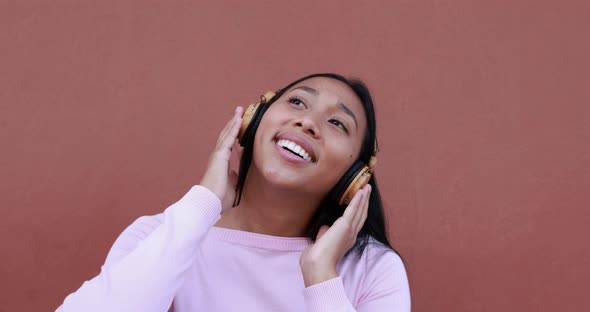 Young latin woman listening music with headphones