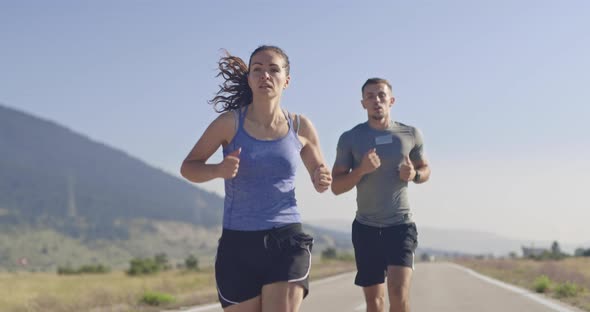 Tracking Slow Motion Shot of Sportive Couple Jogging Outdoors in the Morning Trail Running