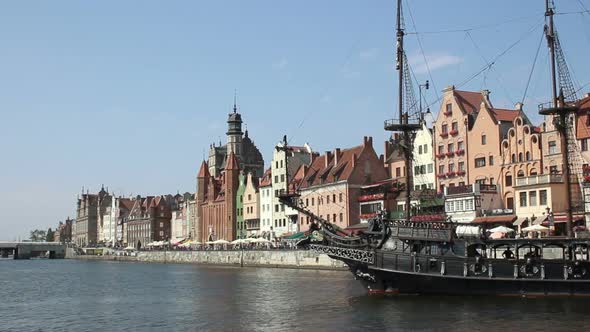 Stylized tourist sail ship turning on river, ancient historical houses on bank