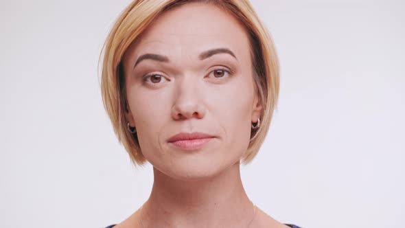 Middleaged Caucasian Blonde Female Fixing Makeup Looking at Camera Touching Hair