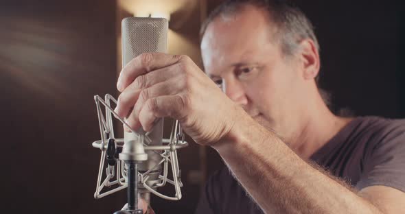 Sound engineer working in a recording studio with a sound console and microphones