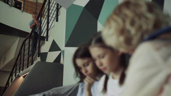 Children Sitting School Corridor Playing Tablet Closeup