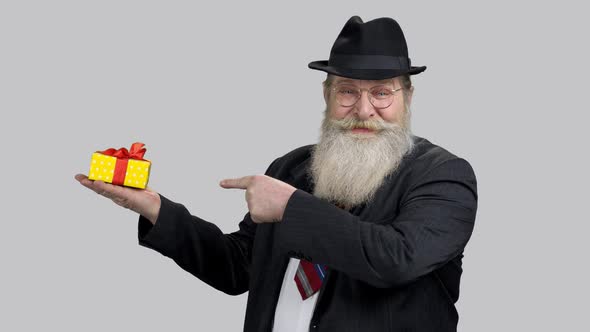 Old Aged Man in Suit Pointing at Gift Box