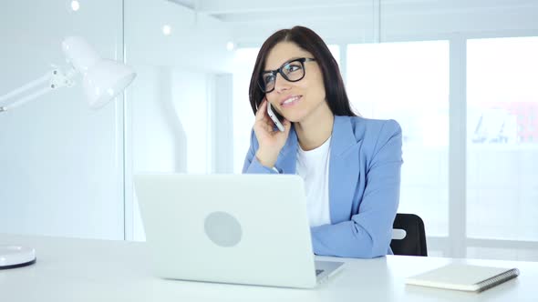 Young Businesswoman Talking on Phone, Attending Call at Work