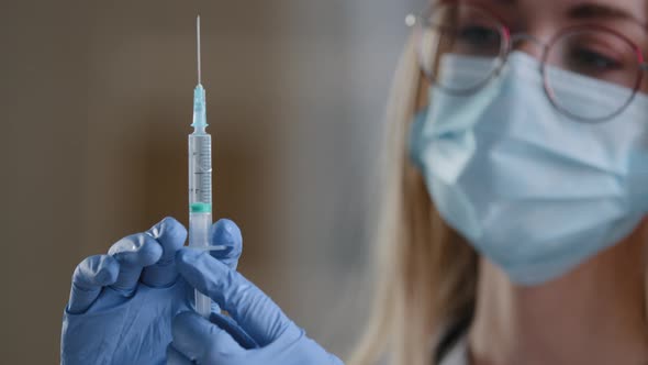 Extreme Close Up Details Woman Doctor in Protective Medical Face Mask Medical Gown Holding Syringe