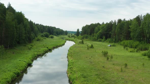 Aerial View of a Car Driving Along the River Bank