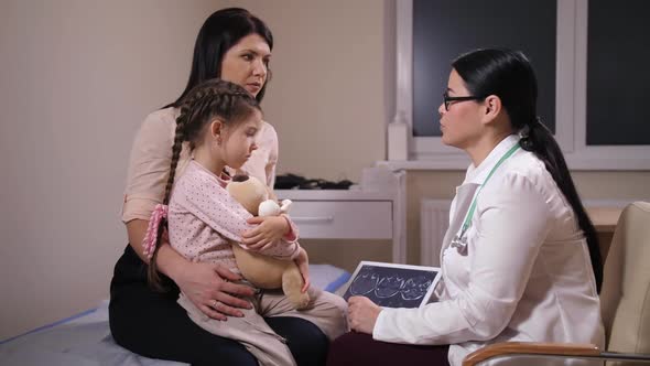 Doctor Showing MRI Results To Mother and Sick Girl