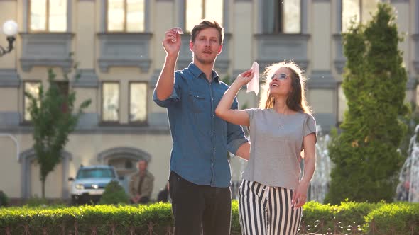 Young Couple Playing with a Paper Aeroplanes Outdoors