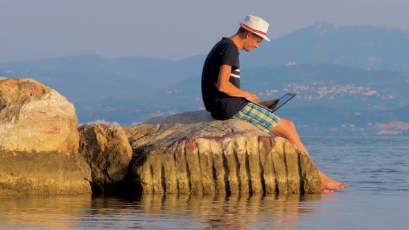 Hipster with Notebook on Sunset Background. Freelancer Working on the Nature. Distant Job Background