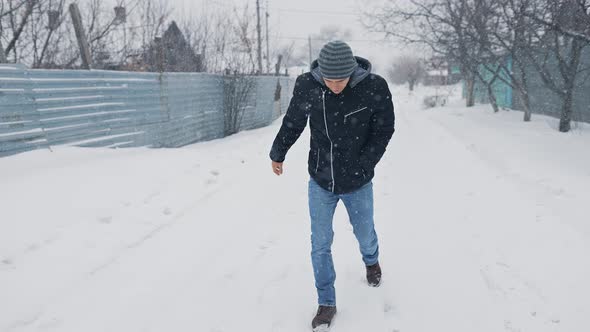 Man Walking Through Snowy Weather and Slips