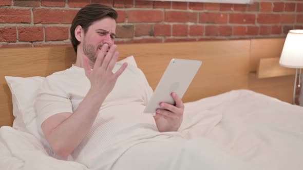 Casual Young Man Reacting to Loss on Tablet in Bed