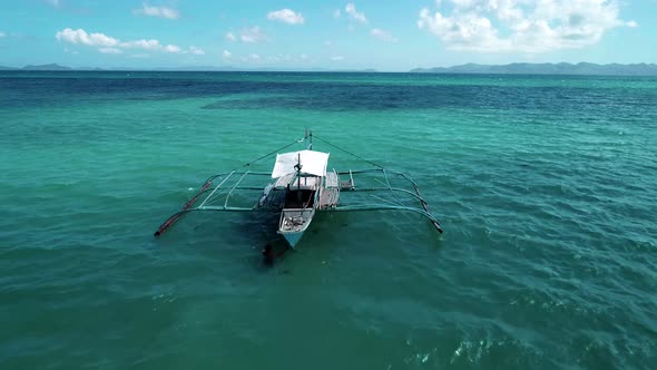 Aerial Shot of a Filipino Touristic Boat Floating in Turquoise Pristine Water