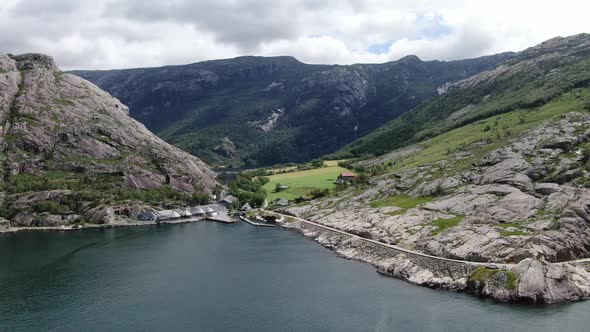 Drone is Flying Over a River in Between the Mountains Farm on the Hills Norway