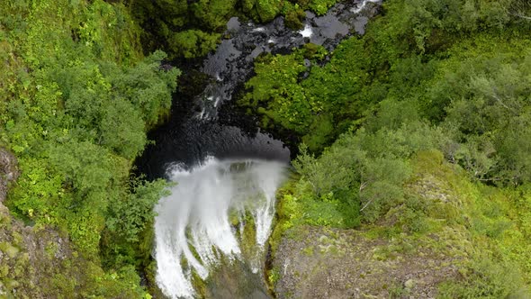 Top View Of Nauthusagil Waterfall Flowing On Steep Rock Mountains In Iceland. Aerial Shot