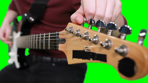 Mid section male musician adjusting tuners