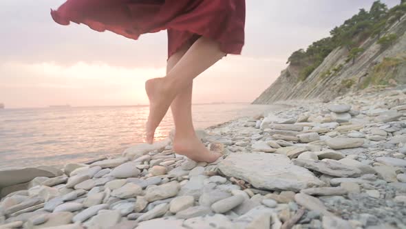 Close-up Slow Motion Following Behind the Legs of a Barefoot Girl in a Red Dress Fluttering 