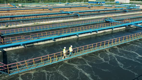 Drone Shot of Two Specialists Walking Across the Bridge at a Water Cleaning Facility