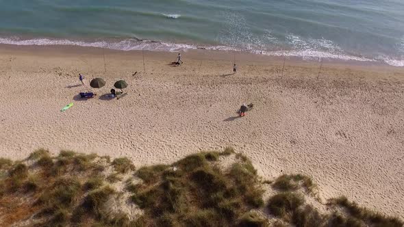 Beautiful coast line with vegetation on one side and the seas hore on the other. A few fisherman are