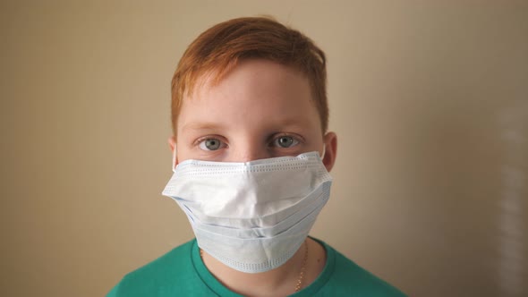 Portrait of Little Boy with Medical Face Mask Looking at Camera. Sad Male Child Wearing Protective