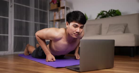 Man using laptop and doing push up