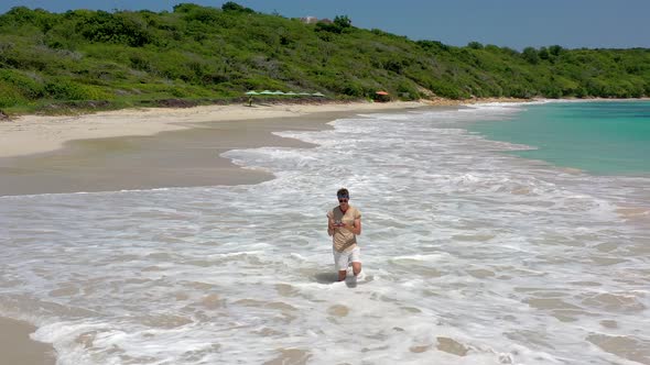 Guy standing in the sea flying a drone,Half Moon bay beach,Antigua,Caribbean.