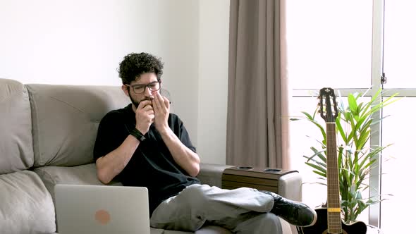 Caucasian adult man plays harmonica following instructions on notebook. Home learning