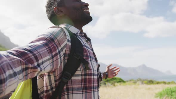 African american man standing with arms wide open while trekking in the mountains