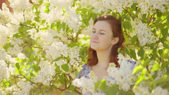 Close View: Happy and Smiling Woman in Lilac Flowers Looks Away