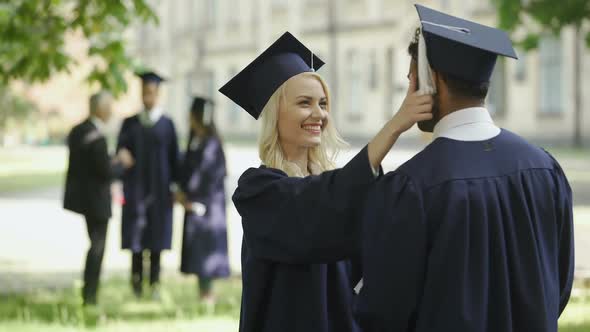 Graduate Female Student Talking to Male Graduate, Touching Hat, Happy Friends