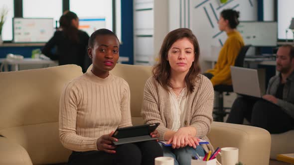 Team From Start Up Company Talking During Video Meeting Sitting on Couch