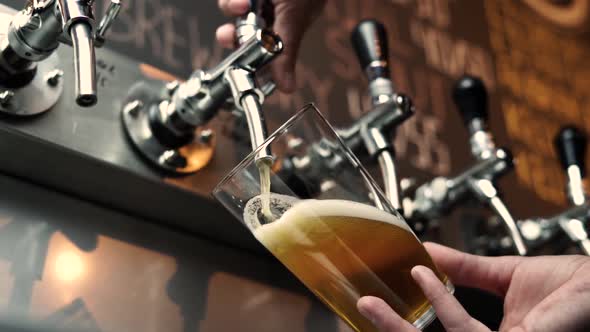 close up view of pouring in beer in a pint from stainless steel tap