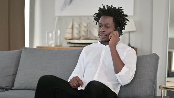 Cheerful African Man Talking on Smartphone at Home 