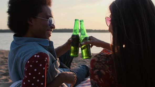 Couple drinking beer and watching the sunset on the beach 