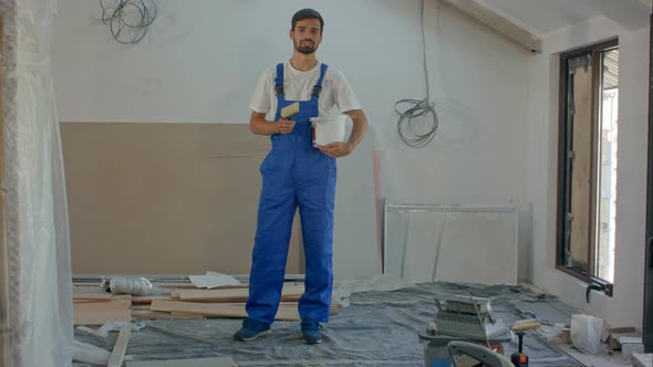 A Young Construction Worker Talks To the Camera - a House Under Construction in the Background