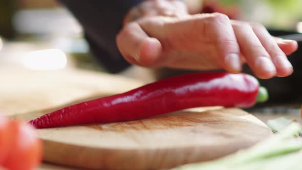 Male Hands Cutting Red Hot Pepper with Knife