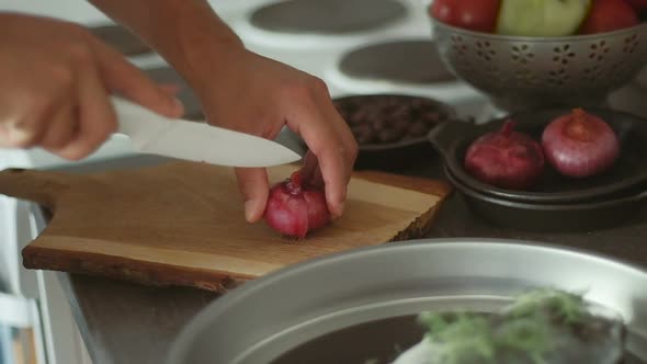 Male hands cutting onions on wooden board. Man is cooking fish with baked vegetables. Slow motion