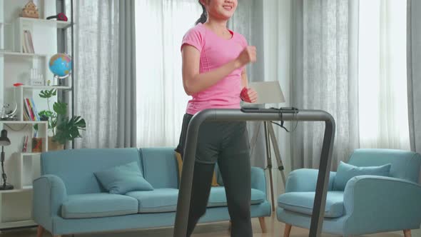 Front View Of Asian Woman Running On A Treadmill At Home