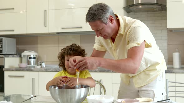 Happy Father and Cute Son Cook Together Breaking Eggs Into Large Dough Bowl