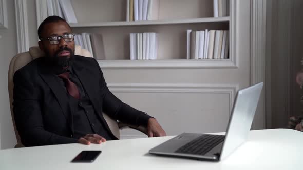 Relaxed Boss in His Working Office in Home, Sitting on Chair in Front of Laptop, Handsome Black Man