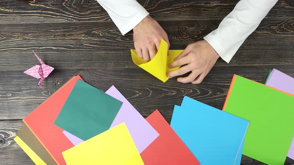 Male Hands Folding Yellow Paper Sheet