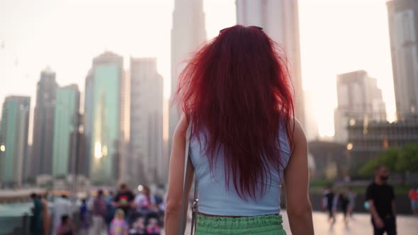 View From the Back a Woman with Red Hair is Walking in the Center of Dubai