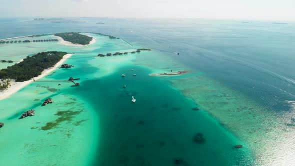 Flying over paradise resorts in ocean with water villas