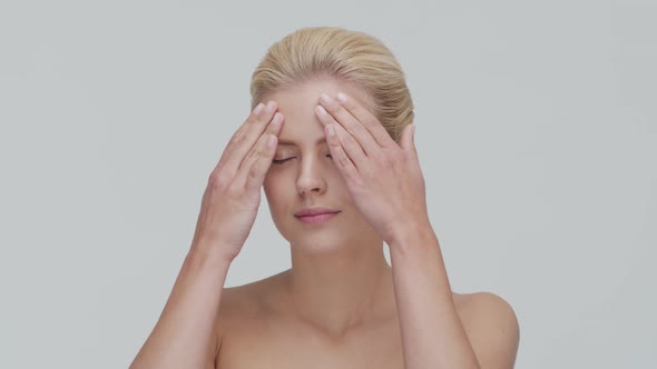 Studio portrait of young, beautiful and natural blond woman applying skin care cream. F