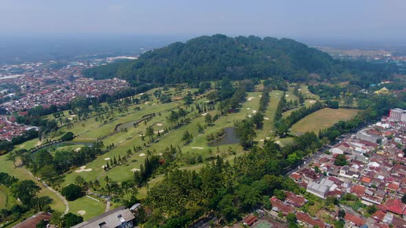 Aerial view of green field of golf course and Tidar Hill in Magelang, Indonesia