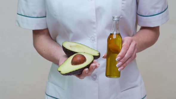 Nutritionist Doctor Holding Organic Avocado Fruit and Bottle of Oil
